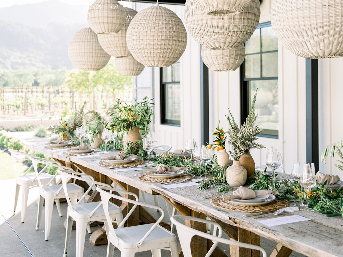 Long farm table set for a dinner party outside on a patio.